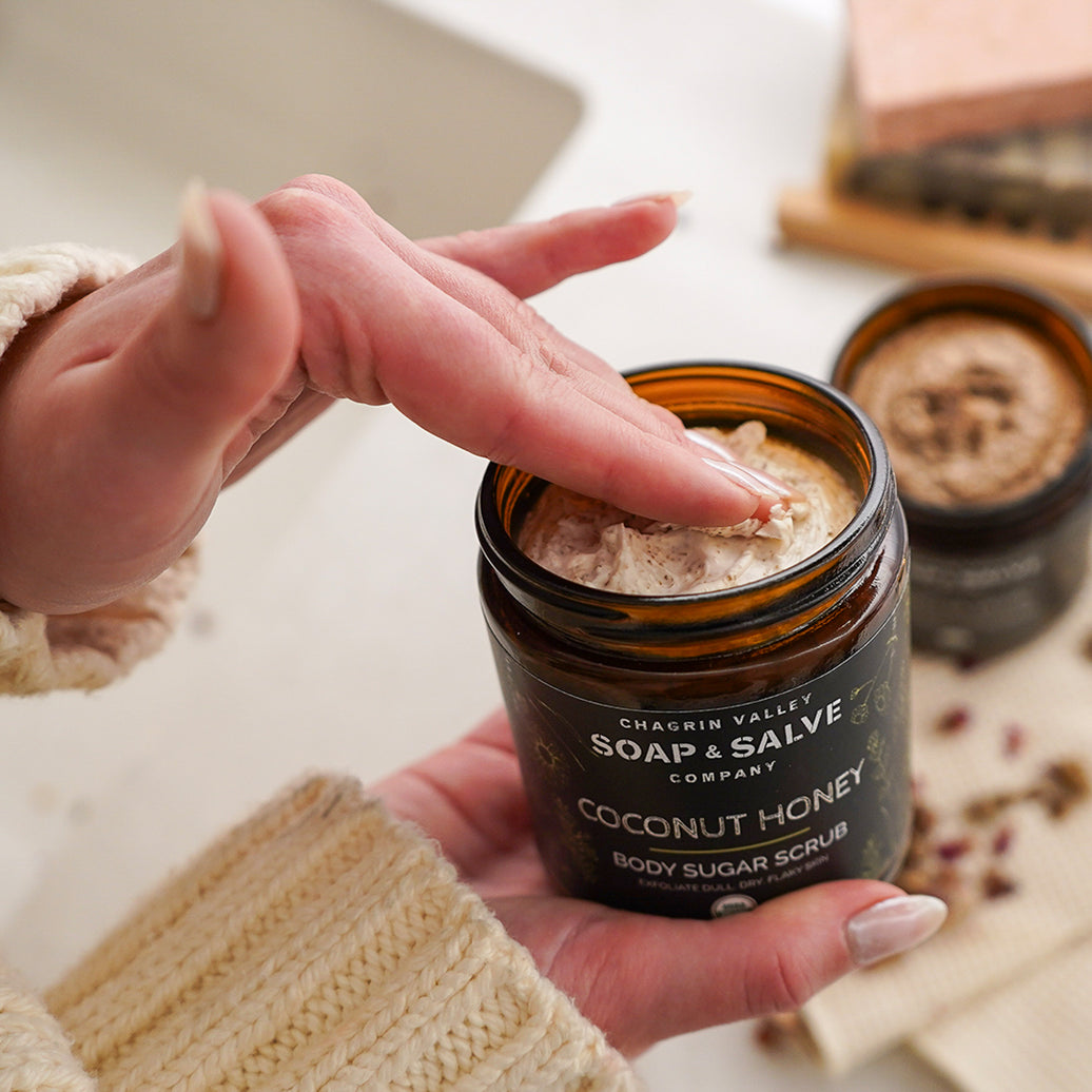 Person holding a jar of Coconut Honey body sugar scrub from Chagrin Valley Soap & Salve Company.