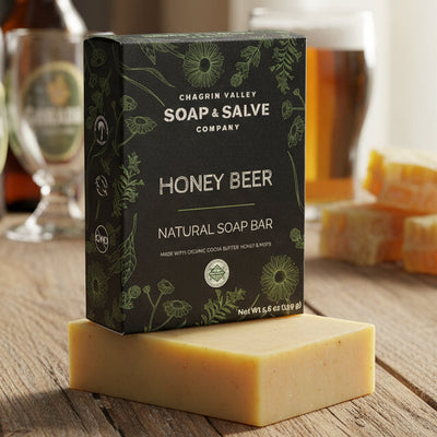 Box of Chagrin Valley Soap & Salve Company Honey Beer soap bar on a wooden table with beer bottles and glasses in the background.