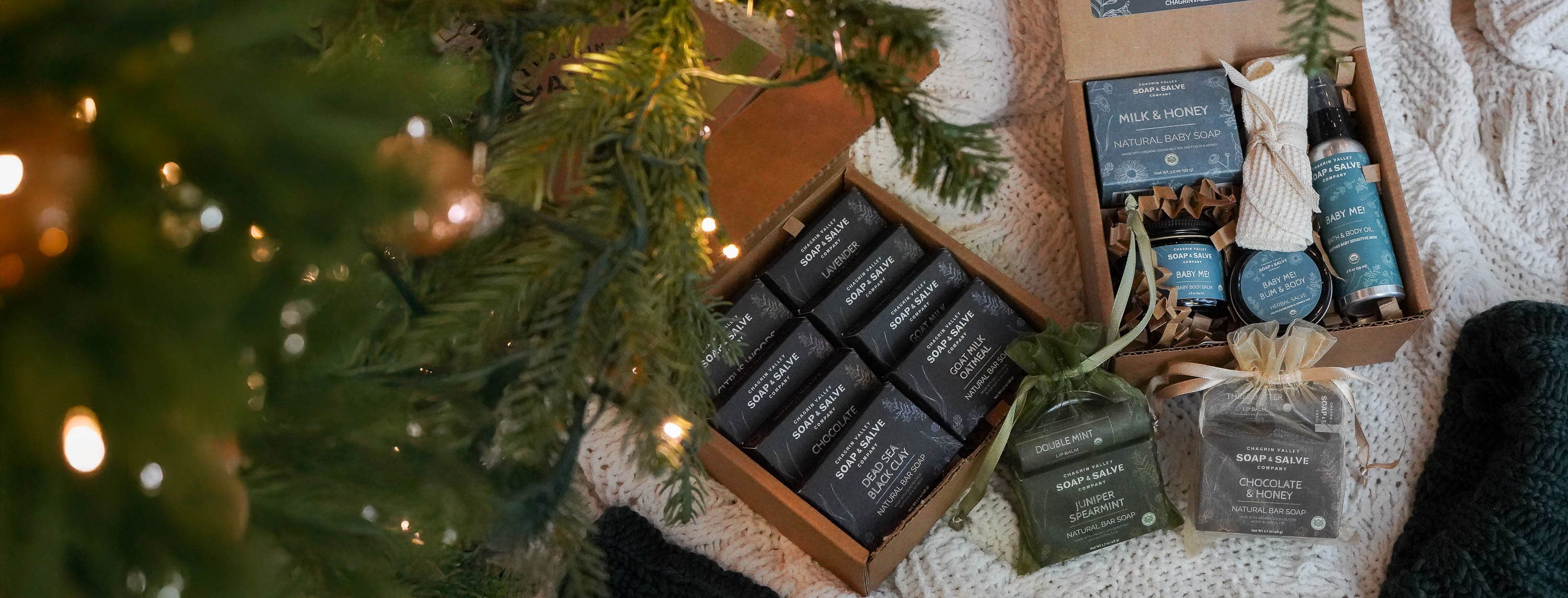 organic soap Gift sets with and skincare on a textured surface with a Christmas tree in the background