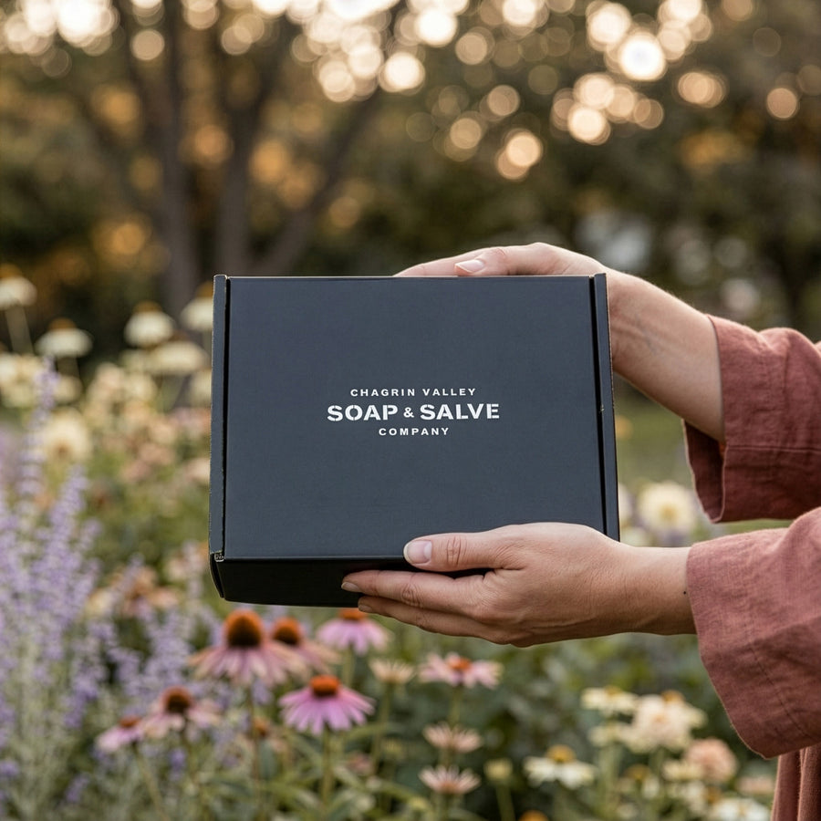 A person holding a organic skincare subscription box in nature.