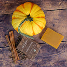 Overhead view of Pumpkin Spice natural soap bar and box with a pumpkin, cinnamon sticks and allspice on rustic wood